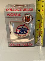 Front view of ornament in box with Winnipeg Jets logo and size reference