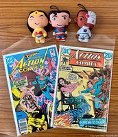 Front view of both Action Comics issues and three plush keychains