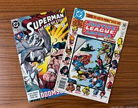 Front covers of both comic books side by side on wood surface