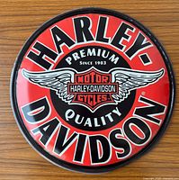 Front view of round Harley-Davidson metal sign showing full logo