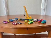 Group view of crane with 13 assorted toy vehicles arranged on table
