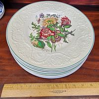 Stack of eight Wedgwood plates showing floral centre and embossed rim