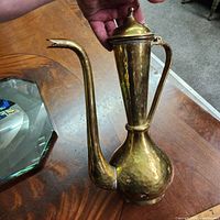 Profile view showing full ewer, hammered body, long spout, lid and handle