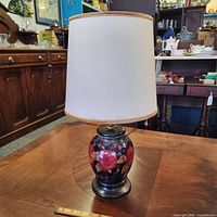 Full view of Moorcroft ceramic table lamp with shade on wooden table