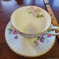Teacup seated on saucer showing floral design and gilt rim