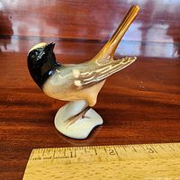Oblique front view of Goebel porcelain Redstart figurine beside ruler for scale