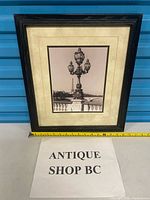 Front view of framed photo showing image, mat, and frame with measuring tape for scale