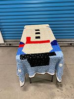 Blanket draped over small table showing overall geometric design and scalloped border