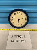 Front view of IKEA wall clock showing dial, hands and blue frame