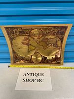 Full view of gold foil world map print with measuring tape showing width