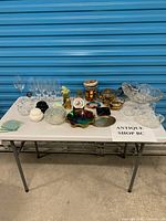 Full lot overview on folding table showing glassware, serveware, decorative pieces
