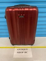 Front view of Samsonite burgundy hard-shell suitcase with measuring tape across base