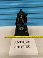 Full view of figure on base with tape measure showing height