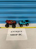 Both monster trucks beside tape measure