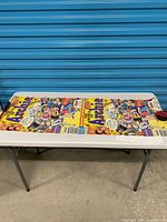 Full poster laid on table showing duplicate cover art panels