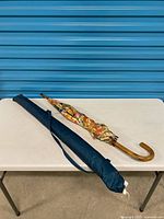 Closed floral umbrella with sleeve on table