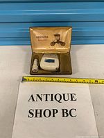 Open case showing shaver and car adapter with measuring tape for scale