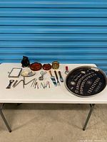 Full lot on table showing tray, tools, figurine, ashtrays, dishes, utensils