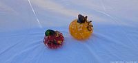 Both glass pumpkins side by side on white surface