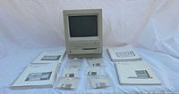 Front view of Macintosh SE with manuals and floppy disks laid out
