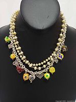 Front view of necklace on display bust showing both strands, glass beads and charms