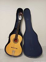AGS classical guitar inside open blue hard shell case