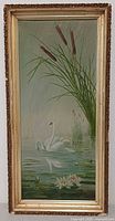 Framed vertical oil painting of swans in pond