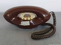 Top view of brown oval rotary phone showing rotary dial and cord