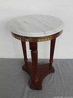 Full view of plant stand front showing marble top, brass gallery, wood legs, and base