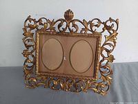 Front view of ornate brass double picture frame showing overall design and two oval openings