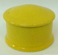 angled view of mustard yellow ceramic box with lid showing glaze craquelure