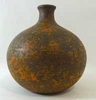 Front view showing spherical form and orange splatter glaze