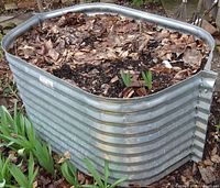 Full view of raised bed planter filled with soil and leaves