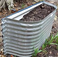 Front view of galvanized steel raised bed planter against garden border