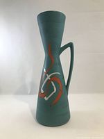 Full front view of turquoise hourglass vase with handle and painted motif