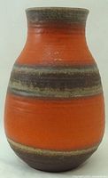 Full view of orange pottery vase with banded glaze