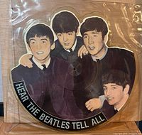 Front view of shaped picture disc with coloured Beatles illustration and title text