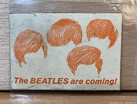 Front of sticker showing orange Beatles hair graphics and text on off-white background