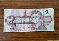 Obverse showing denomination 2, CANADA text, portrait of Queen Elizabeth II, slight tear and creases visible