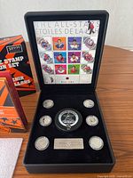 Open presentation case showing stamp sheet, central large medallion, four smaller medallions and numbered plaque