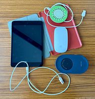 Front view iPad Mini with charge cord, red case, Apple Magic Mouse, Vaydeer mouse mover, green Helix charging pad