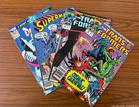 all four comic books fanned out on wooden surface showing covers