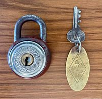 Padlock closed alongside key and brass key fob