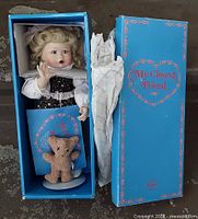 Doll, bear, stand, paperwork and box visible inside original packaging