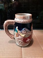 Front view of ceramic beer stein showing relief scene and handle