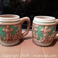 Front view of both porcelain beer mugs showing relief scenes and handles
