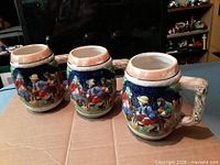 Three relief ceramic beer mugs side view