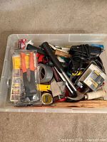Top view of plastic bin showing assorted hand tools and supplies