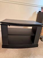 Front view of black laminated TV stand showing two open shelves and matte finish