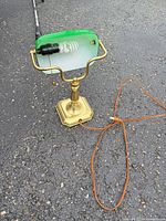Full view of brass banker lamp with cord and CFL bulb visible
